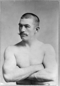 19th century photo of a strong man, bare chested and sporting an impressive mustache