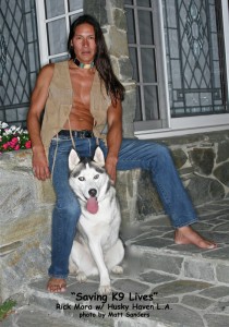 Rick Mora with husky. Rick is wearing an open vest. We envy the husky.