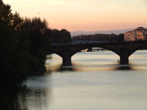 View of the Arno River in Florence, sun setting behind it