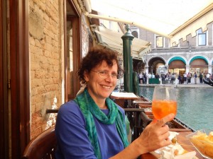 Raising a glass of Aperol spritz in a bar by a Venetian canal