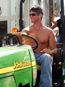 Buff, shirtless man on a lawn tractor