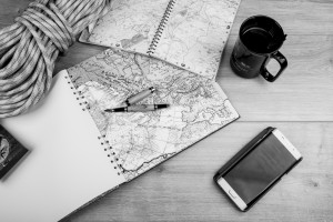 Maps, notebook, coffee mug, smartphone, as if someone were planning a journey.